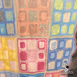 Multicolor granny square crochet blanket featuring bright rainbow tones