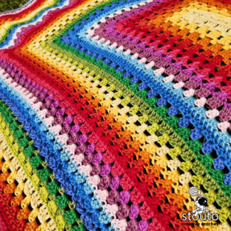 Rainbow striped crochet baby blanket in bright colorful rows
