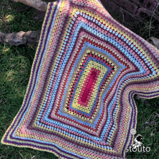Scrap yarn baby blanket crochet pattern worked in the round using colorful leftover yarn