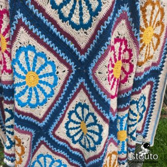 Spring inspired crochet blanket featuring bright daisy flower motifs