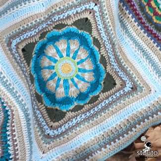 Decorative floral granny square crochet motif featuring layered petals and textured stitch techniques.