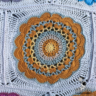Large crochet granny square featuring floral-inspired stitches 