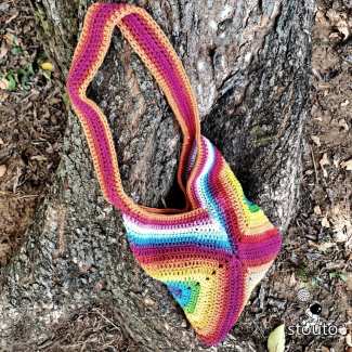 Side view showing the construction of a handmade granny square crochet tote bag. 