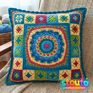 Colourful granny square crochet pillow with blue, pink, green and cream flower motifs