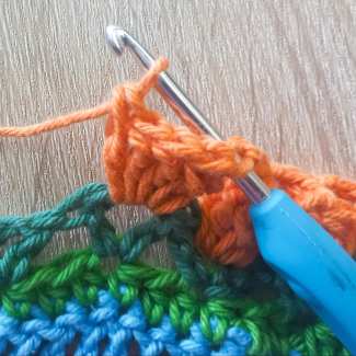Push hook from the front into first dc stitch, then back into loop of the 5th dc stitch, pull yarn,