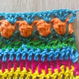 The stitch pattern repeats with 3 dc into each popcorn stitch of the row,