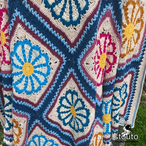 Spring inspired crochet blanket featuring bright daisy flower motifs