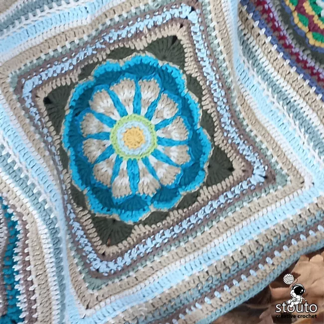 Decorative floral granny square crochet motif featuring layered petals and textured stitch techniques.