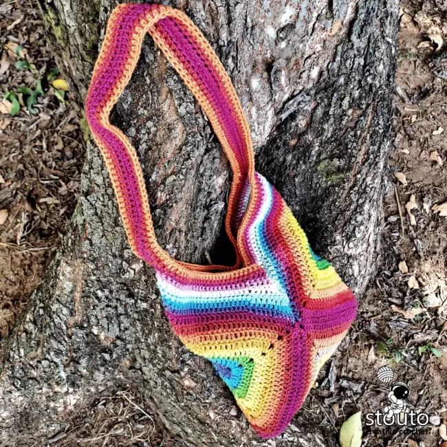 Side view showing the construction of a handmade granny square crochet tote bag. 